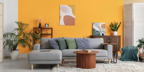 Interior of living room with comfortable sofa and coffee table near yellow wall