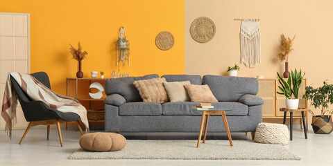 Comfortable grey sofa, pouf and table in interior of light living room