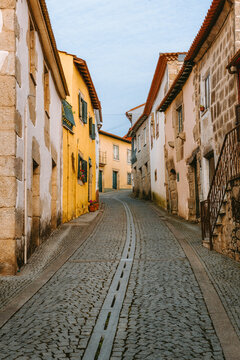 Charming cobblestone street winding uphill between colorful houses adorned with potted plants and tiled roofs in Ucanha, Tarouca, Viseu district, Portugal