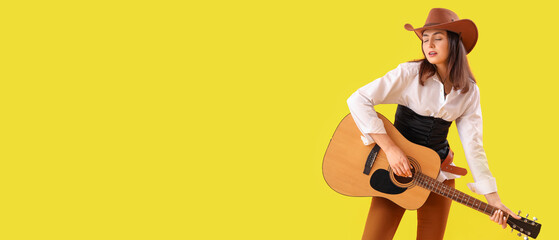 Beautiful cowgirl playing guitar on yellow background