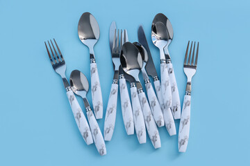 Stainless steel cutlery with plastic handles on blue background