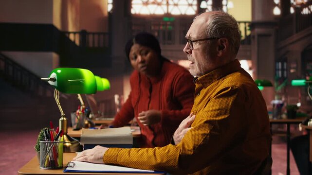 Senior adult in hyperventilation crisis feeling unwell in the campus library, having difficulty breathing and showing vulnerability. Old student having a panic attack emergency. Camera A.