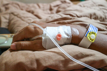 IV or intravenous drip in patient hand and warning of fall risk for patient in hospital