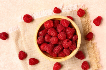 Wooden bowl with fresh raspberries on light background