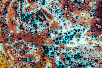 Abstract close-up of colorful chemical reaction with bubbles and fluid textures in macro view.