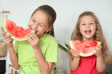 Happy little girls eating fresh watermelon in kitchen