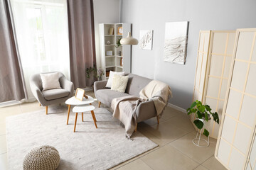 Interior of modern living room with grey sofa, armchair and coffee table