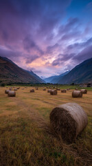 Dramatic sunset over a field of hay bales in a mountain valley