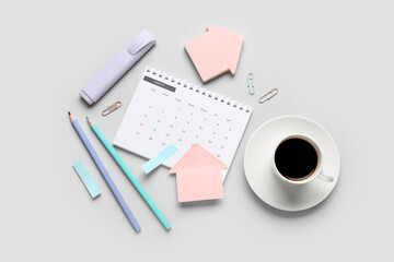 Calendar with cup of coffee and office stationery on grey background