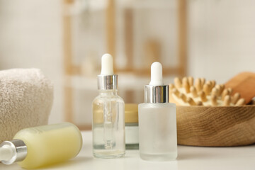Bottles of cosmetic oil and bath supplies on table in bathroom, closeup