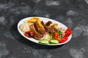 Lamb rack with vegetables, rice, and French fries in bright overhead rustic composition