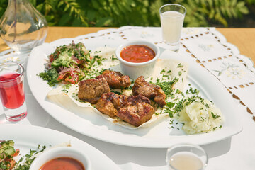Pork shashlik served with vegetable salad, bright outdoor lighting, overhead composition