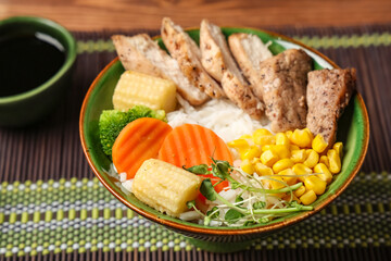 Bowl of tasty rice with chicken and vegetables on table, closeup