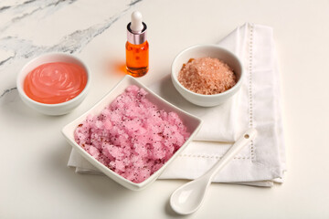 Bowls with scrub and ingredients on light background