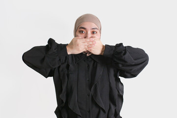 Portrait of woman wearing hijab and black blouse with gesture covering her mouth with hands on...