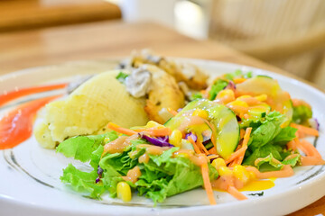 Close up view of chicken creamy mushroom with vegetables on white plate. Blur, bokeh. Wooden table And chair.