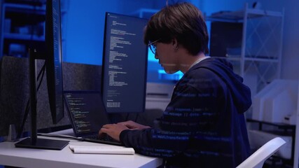 Focused Asian young adult programmer coding complex software solutions multiple screens in a dark office environment - Powered by Adobe
