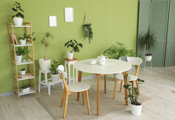 Interior of dining room with table, shelf unit and green plants