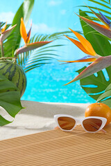 Obraz premium Flatlay of sunglasses, oranges, and bird-of-paradise flowers arranged beside soft sand and palm leaves. Summer beach theme with ample space for placing cosmetic or lifestyle product mockups.