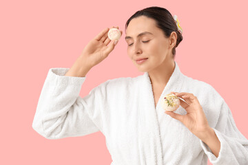 Smiling young woman with bath bombs on pink background
