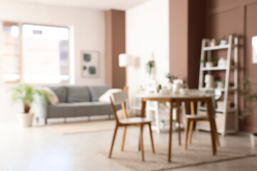 Blurred view of living room with green plants, sofa and dining table