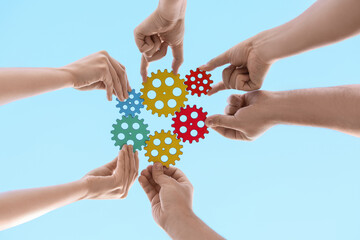 Many hands with colorful gears against sky, bottom view