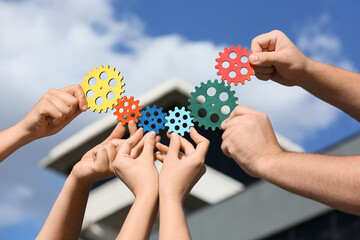 Many hands with colorful gears outdoors