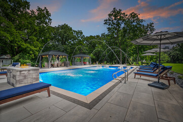 Twilight view of luxury pool house with water fountain feature and stunning outdoor setup