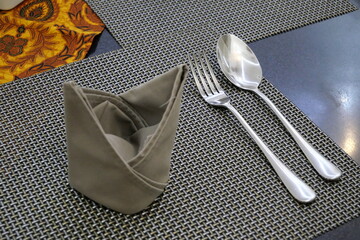 Cutlery and napkin prepared on a table in a restaurant.