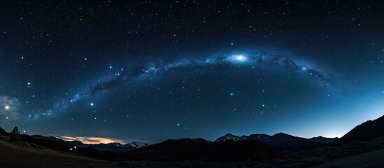Panoramic night landscape showcasing a vibrant Milky Way arching over a dark mountain range under a star-studded sky