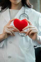 Close-up of a healthcare professional holding a red heart, symbolizing care and wellness in a...