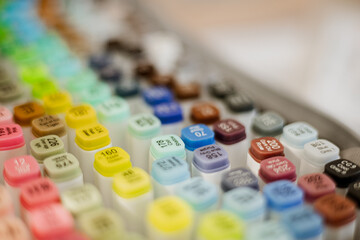 Close-up of colorful marker tops arranged in rows, showing numbers and shade names in focus