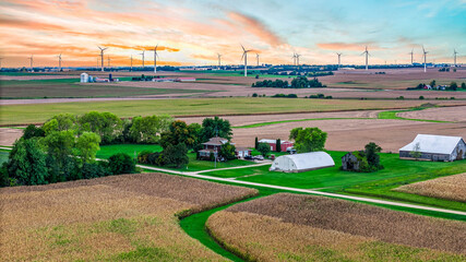 Fototapeta premium Aerial View of Farm Fields with Wind Turbines on the Horizon