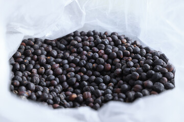 Close-up view of raw coffee beans on white bag before roasting.
