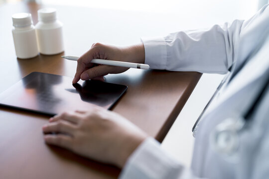 Doctor using stylus and digital tablet for patient data entry or medical chart updates, healthcare digitization, electronic prescriptions and mobile health technology for efficient workflow.