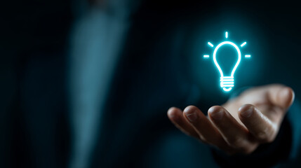 Innovative glowing light bulb icon floating above open hand symbolizing bright idea and creativity in dark background
