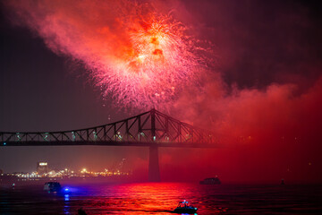 Drone flight through holiday fireworks above water with reflection on the black sky background