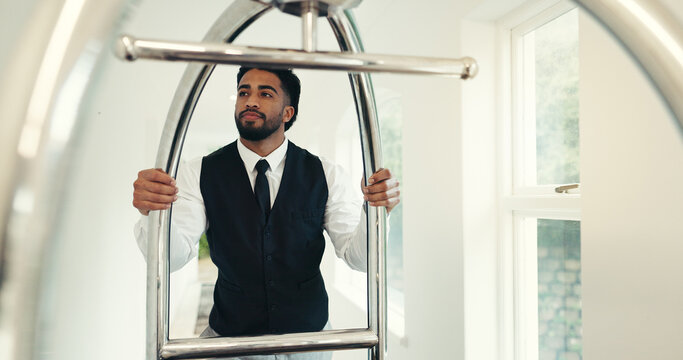 Porter, service and push trolley in hotel for luggage handling, check in welcome and guest arrival. Employee, hospitality and man with cart at luxury resort for bellboy assistance, concierge and help