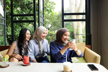 Three Asian friends Hanging Out at cafe restaurant, Looking at Mobile Phone