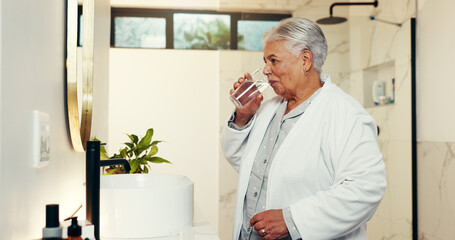 Drinking water, morning and senior woman in bathroom, thirsty and wellness with retirement. House,...
