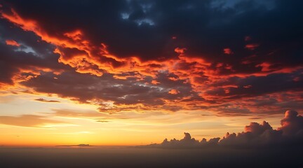 Obraz premium Fiery orange and red clouds at sunset over a hazy horizon image