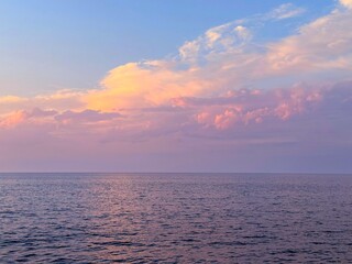 Sunrise sky clouds over calm rippling sea water.