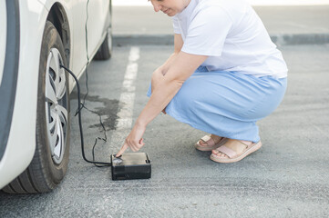 A woman pumps up a tire on a car. 