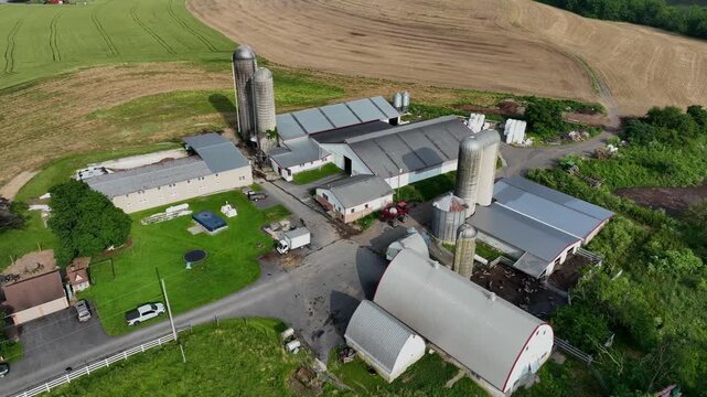 Aerial view of American farm with barns, silos and fields. Classic rural USA agriculture scene showing buildings, equipment and farmland on a sunny summer day. Top down. Garden and hilly fields