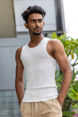 Handsome and good looking Gen Z male model with a fashionable black haircut, is posing in a trendy outfit with a gym fit muscled body