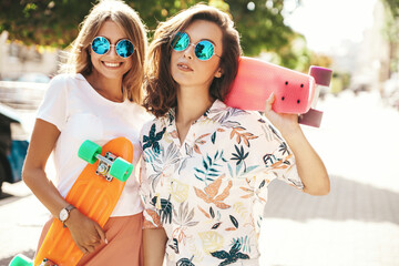 Two young stylish smiling hippie brunette and blond women models in summer sunny day in hipster...