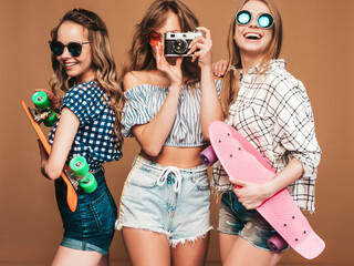 Three beautiful stylish smiling female with colorful penny skateboards.Women in summer hipster...