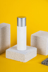 Plastic white tube for cream or lotion. Skin care or sunscreen cosmetic with stylish props on yellow background.