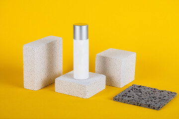 Plastic white tube for cream or lotion. Skin care or sunscreen cosmetic with stylish props on yellow background.