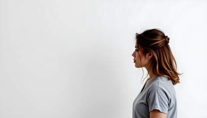 Fototapeta premium a moment of solitude and introspection. a person, clad in a casual t shirt, stands in profile against a white background, their back to the viewer